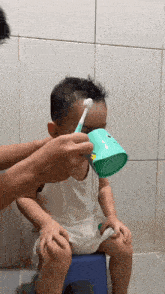a person is brushing a child 's hair with a toothbrush and a cup
