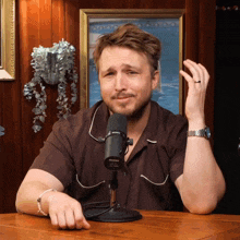 a man sitting in front of a shure microphone making a funny face