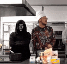 a man in a chef 's hat is standing next to a man in a hood