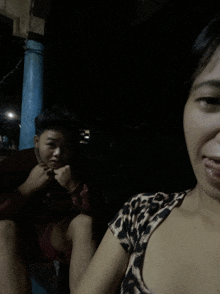 a woman in a leopard print shirt sits next to a man in a red shirt