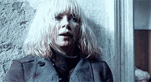 a woman with blood on her face is standing in front of a wall .