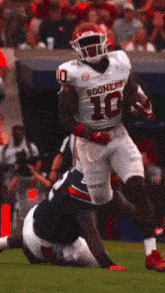 a football player wearing a white jersey with the number 16 on it is running on the field .