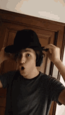 a young man wearing a black hat and headphones making a funny face