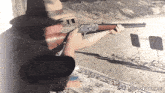 a man with a tattoo on his arm holds a rifle in front of a sign that says giffun.com
