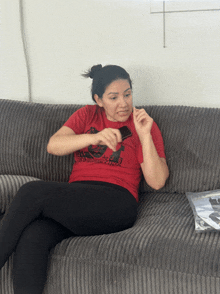 a woman is sitting on a couch wearing a red shirt that says ' avengers ' on it