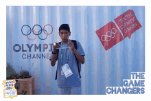 a young man stands in front of a wall that says olympic channel