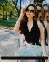 a woman wearing sunglasses sitting on a bench in a park