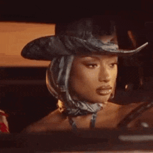 a close up of a woman wearing a cowboy hat and scarf .