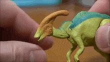 a person is holding a small toy dinosaur with a long neck