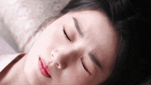 a woman is laying down with her eyes closed and her mouth open .