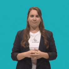 a woman wearing a eversa t-shirt stands with her hands folded