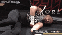 a man with a beard is laying on the ground with a sign that says njpw world