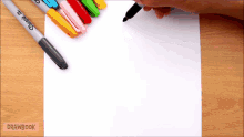a person is writing on a piece of paper with sharpie pens