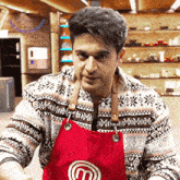 a man wearing a red apron that has the letter m on it