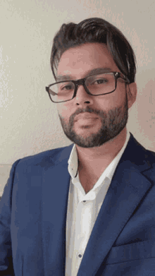 a man with glasses and a beard wearing a blue suit