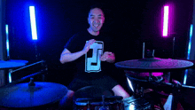 a man wearing a black shirt with the letter t on it is playing drums