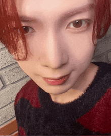 a close up of a person 's face wearing a red and black sweater