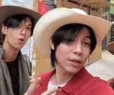 two men wearing cowboy hats pose for a picture