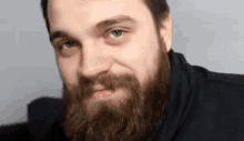 a man with a beard is making a funny face while looking at the camera .