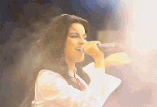 a woman singing into a microphone with a blurry background and the word angels visible in the corner