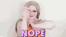 a woman is making a funny face and pointing at the word nope .
