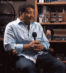 a man in a striped shirt is sitting in front of a bookshelf with a sign that says star talk on it