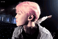 a young man with pink hair is wearing headphones and a striped shirt