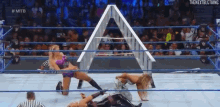 a group of women are wrestling in a wrestling ring with a referee watching .