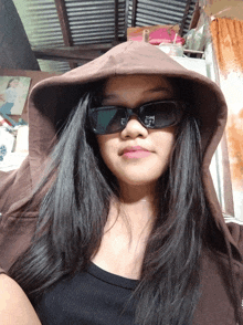 a woman wearing sunglasses and a hooded jacket looks at the camera