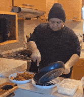 a man cooking in a kitchen with a necklace that says l on it