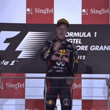 a man in a red bull shirt stands on a podium