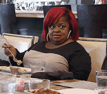 a woman with red hair is sitting at a table eating