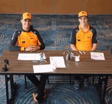 two men sit at a table with one wearing a shirt that says dkk