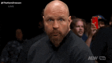 a bald man with a beard wears a black shirt that says aew