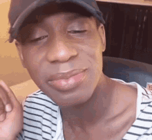 a man wearing a hat and a striped shirt is looking at the camera