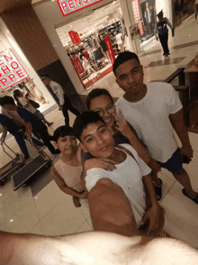 a group of people are posing for a picture in front of a store that has the word pen on it