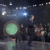 a man in a suit is dancing on a stage in front of a crowd