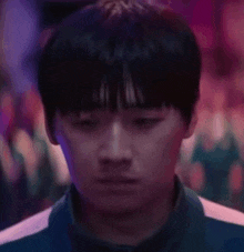 a close up of a man 's face in a dark room with a crowd in the background .