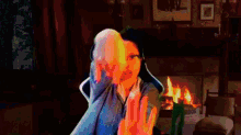 a woman with glasses is sitting in front of a fireplace in a dark room
