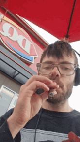 a man wearing headphones smoking a cigarette in front of a dairy queen sign