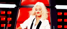 a woman is sitting in a red chair with her eyes closed and making a funny face .