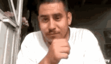 a man in a white shirt is making a funny face with his fist in the air .