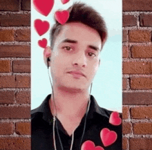 a young man wearing headphones and a black shirt is standing in front of a brick wall with hearts flying around him .