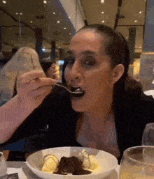 a woman is eating a dessert with a spoon in her mouth