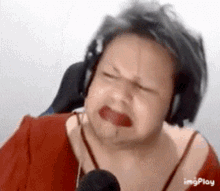 a man wearing headphones and a red shirt is making a funny face .
