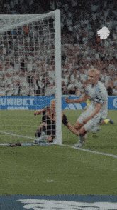 a soccer player jumps in the air to celebrate after scoring a goal in front of a banner that says unibet