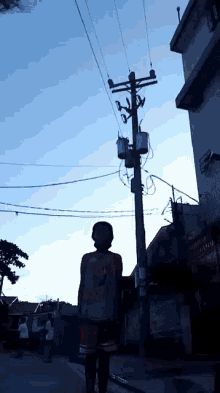 a man stands in front of a telephone pole