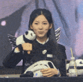 a woman holding a stuffed panda bear with wings on it