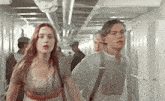 a man and a woman are walking down a hallway