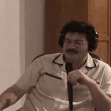 a man is wearing headphones and holding a microphone while sitting in a chair .
